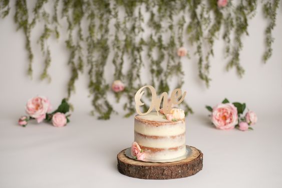 a cake with the word love on it sitting on a piece of wood in front of flowers