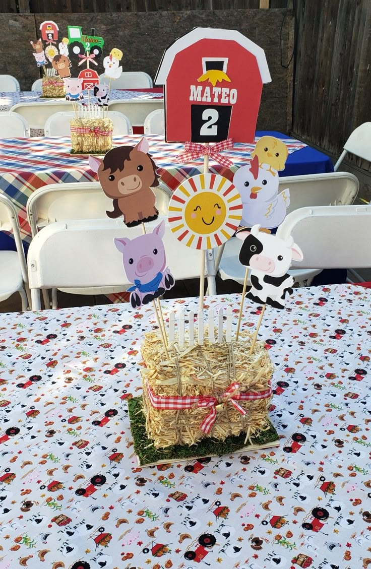 a table topped with straw bales filled with cake pops and farm animals on top of it