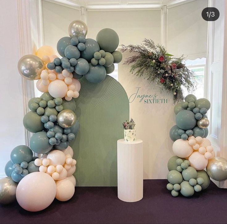 an arch made out of balloons and greenery is displayed in front of a doorway