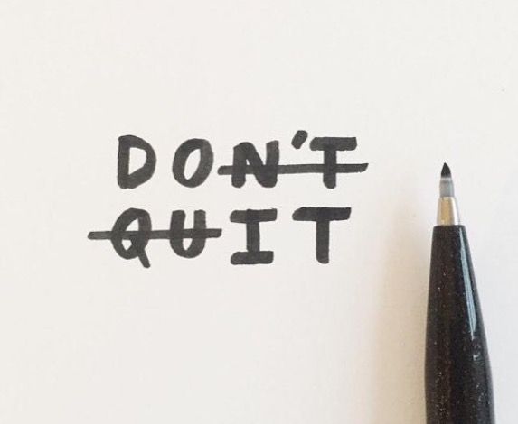 a black pen sitting next to a piece of paper with the words don't quit written on it