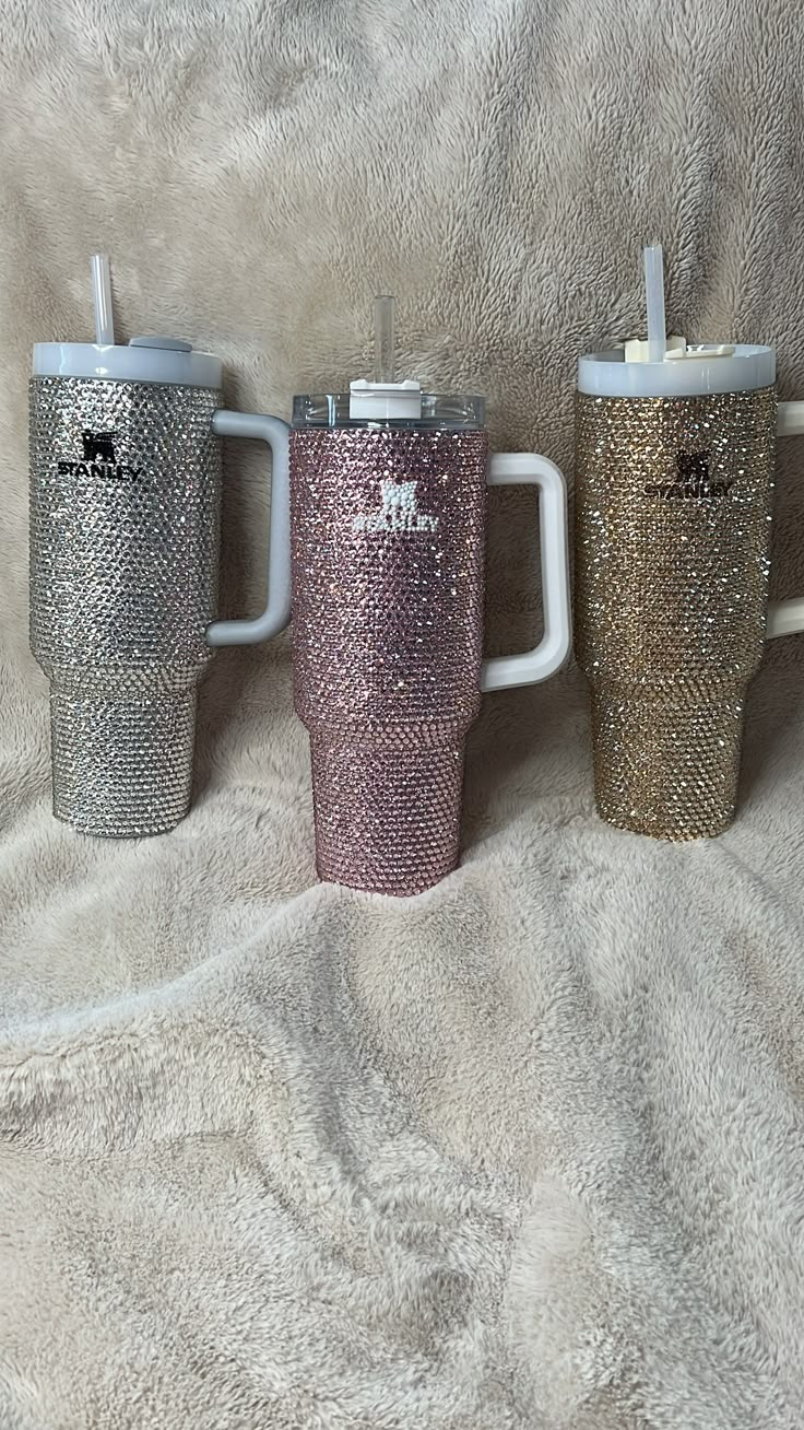 three different colored coffee mugs sitting next to each other on a white blanket,