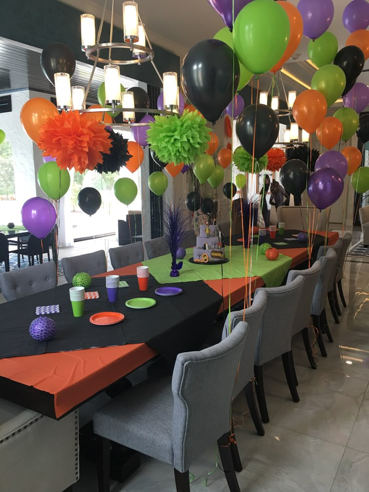 a long table with many balloons and decorations on it in the middle of a room