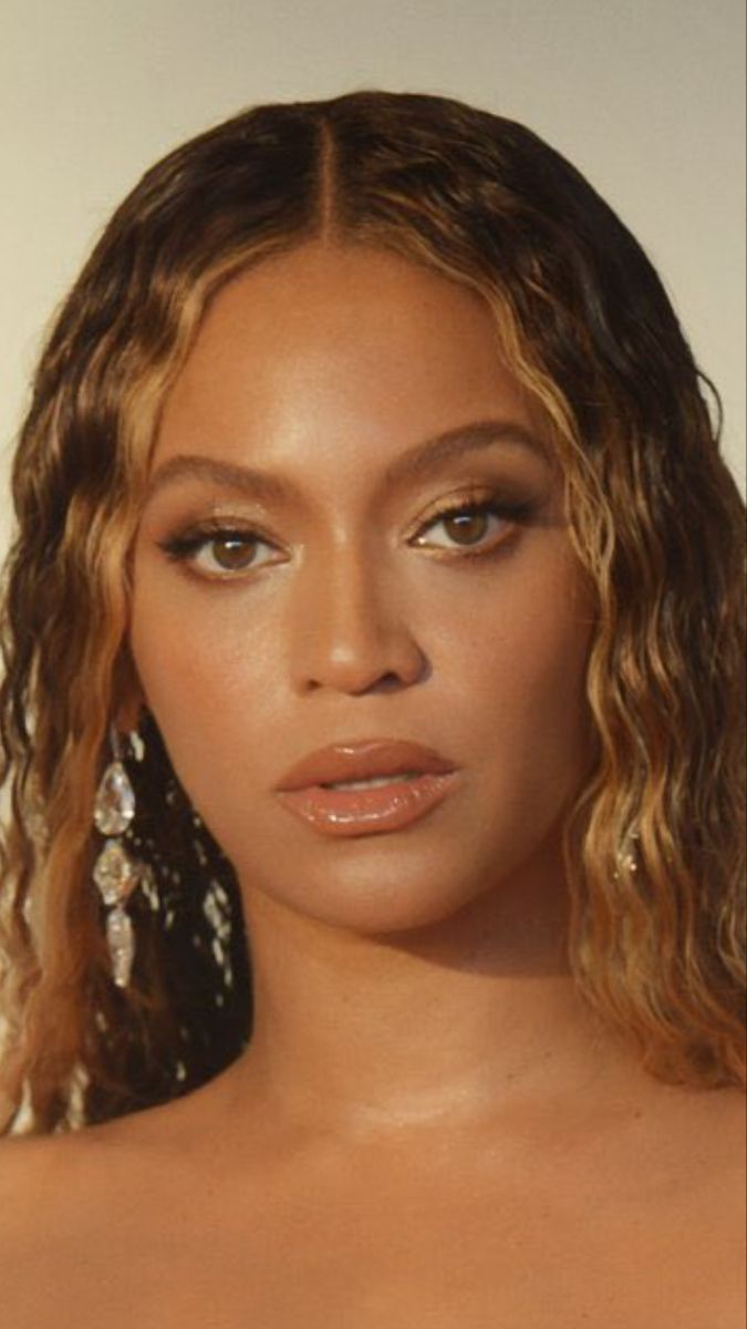 a close up of a person with long hair and earrings on her head, wearing an off - white dress