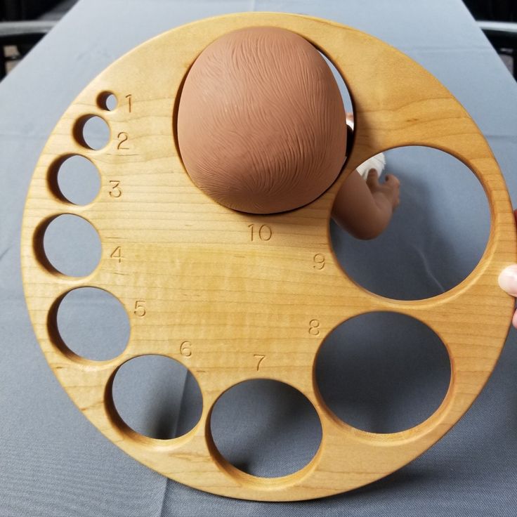 a wooden clock with an infant's head in the center and numbers on it