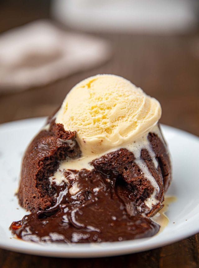 a piece of chocolate cake with ice cream on top is sitting on a white plate