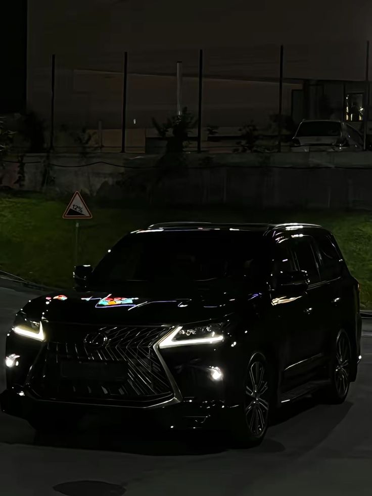 a black car driving down a street at night