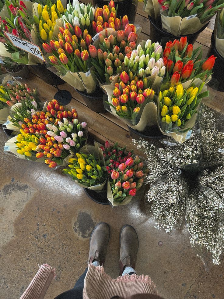 a person's feet are standing in front of many different colored tulips