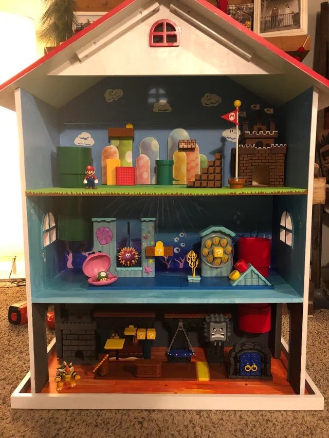 a doll house with lots of toys on top of the shelves in front of it