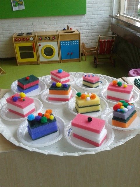 there are many small cakes on the plate and one is pink, blue, green, yellow and white