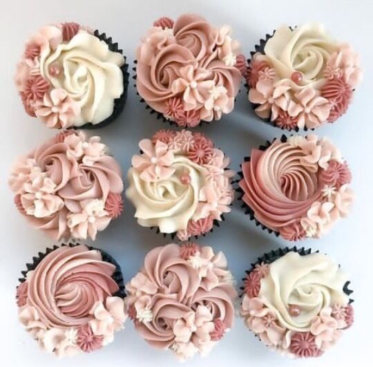 twelve cupcakes with pink and white frosting flowers on each one are arranged in a circle