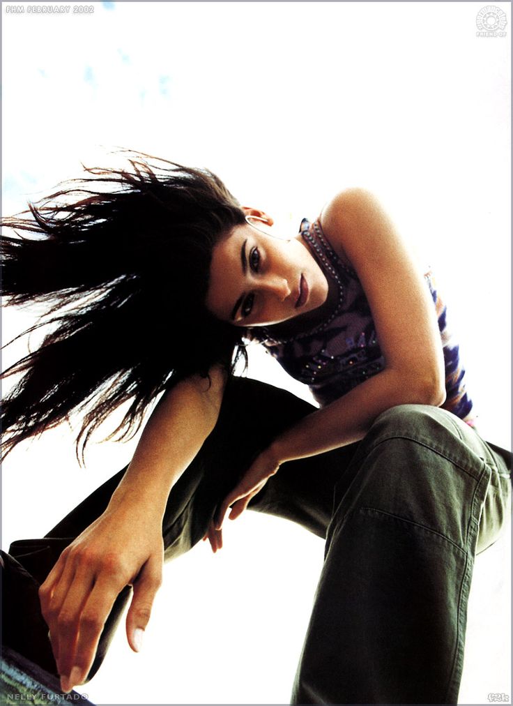 a woman with long hair sitting on the edge of a skateboard in mid air