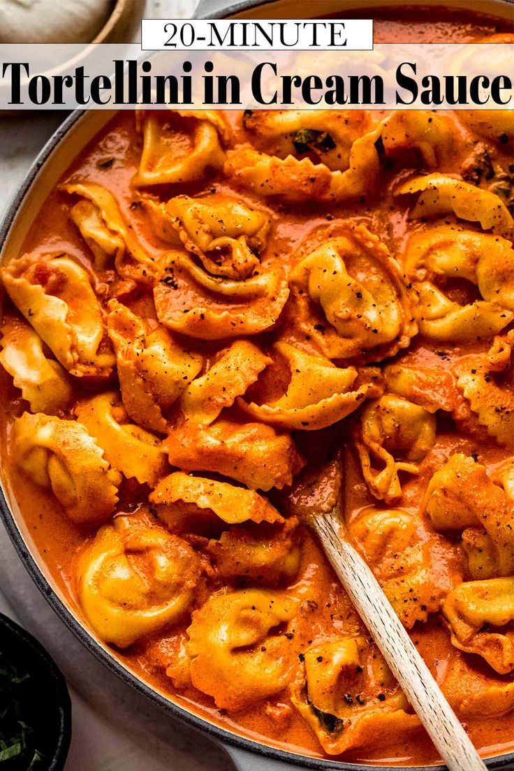 a pan filled with tortellini in cream sauce on top of a white table