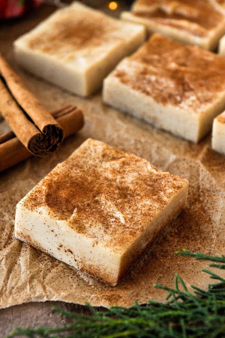 cinnamon sugar bars are sitting on wax paper next to cinnamon sticks and an evergreen branch