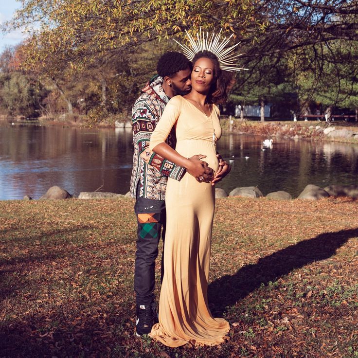 a man and woman standing next to each other in front of a lake wearing headdress