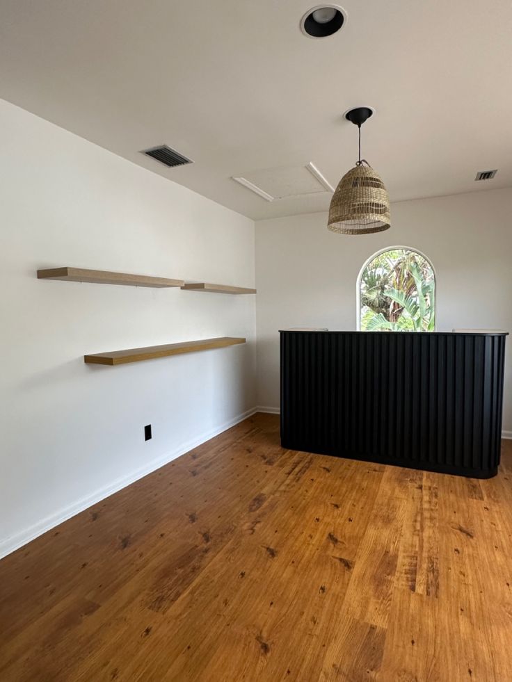 an empty room with wood floors and white walls