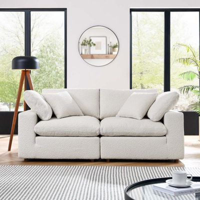 a living room with a white couch and table in front of large windows, potted plants on the floor