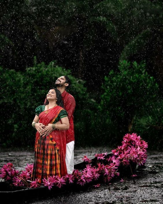 a man and woman standing on top of a boat in the rain