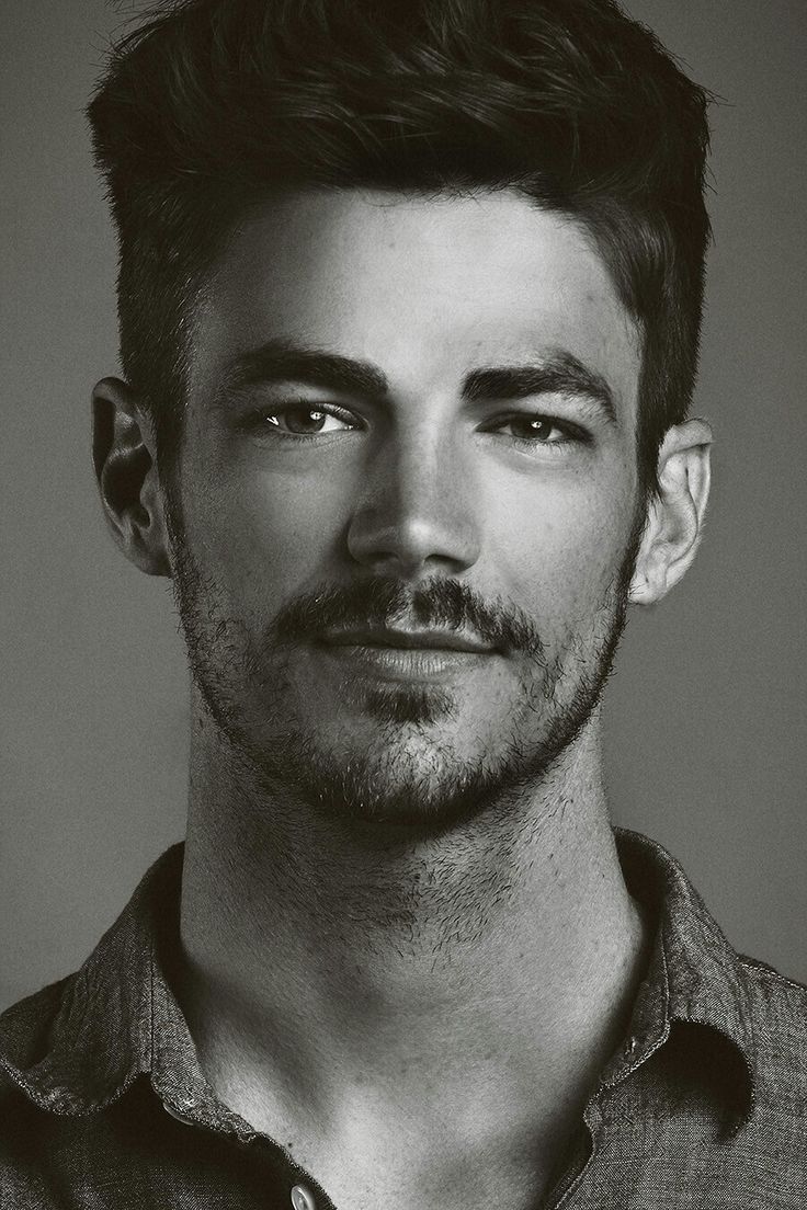 a black and white photo of a man with a goatee mustache looking at the camera