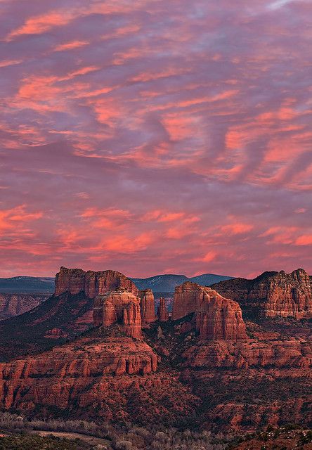 the sky is pink and purple as the sun sets in the mountains behind it,