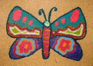 a colorful butterfly is shown on the floor in front of a brown background with pink, blue and green dots