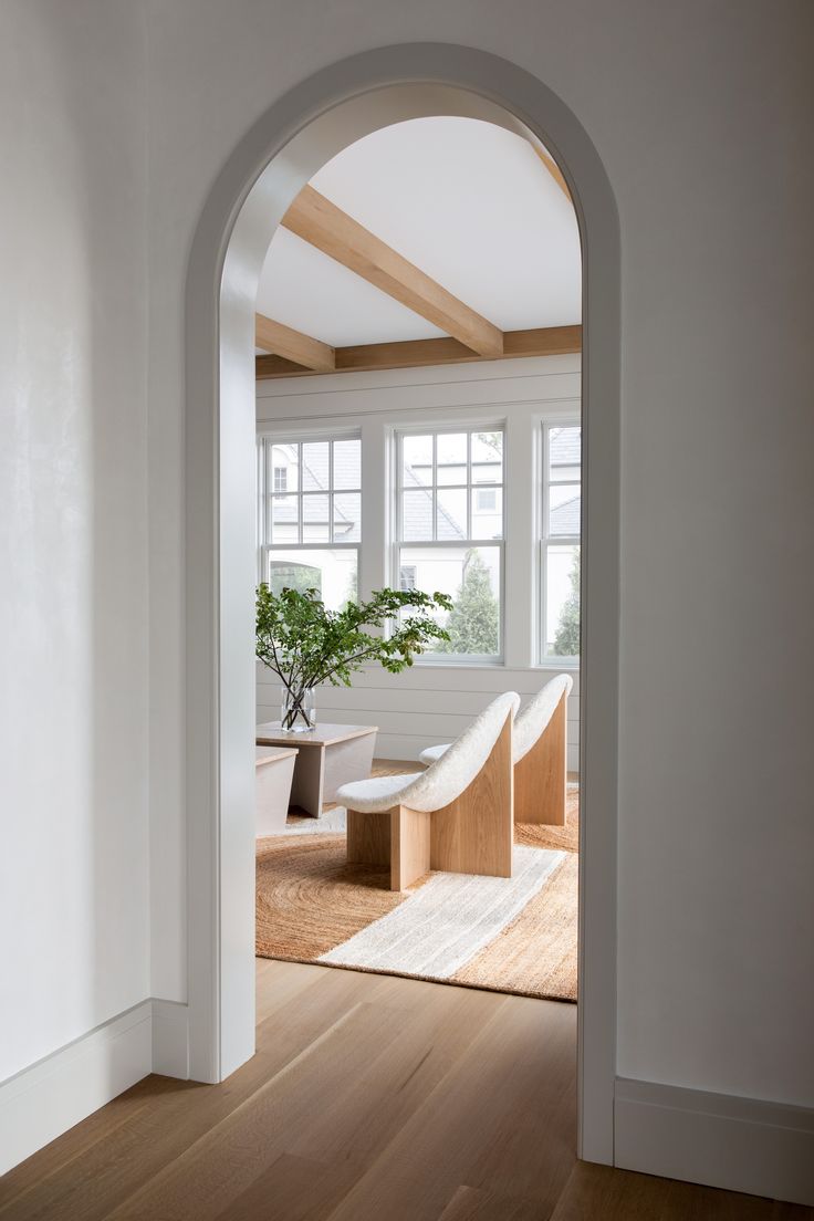 an archway leading into a living room with white walls and wood floors, along with a bench in the center