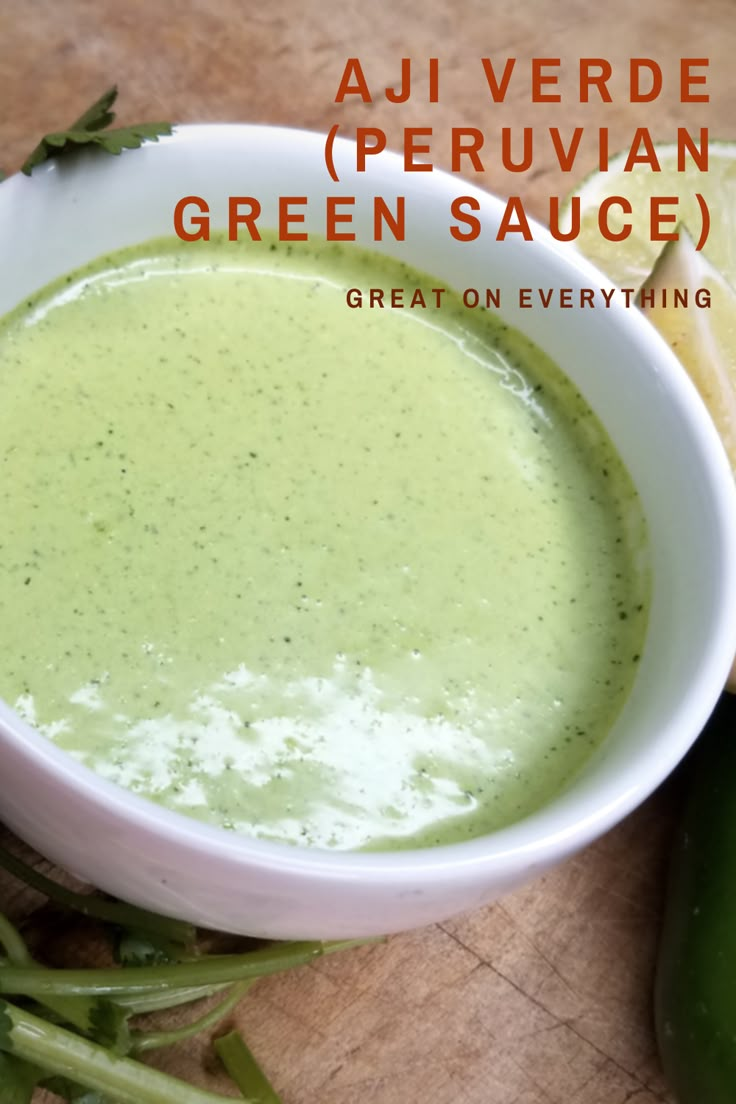 a white bowl filled with green sauce on top of a cutting board next to sliced vegetables