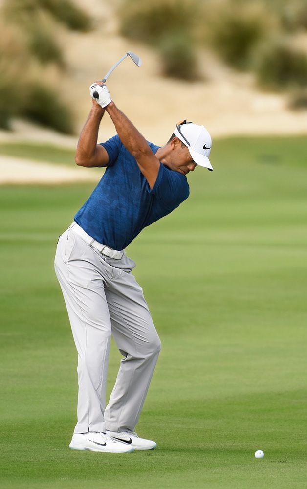 a man in blue shirt and grey pants playing golf