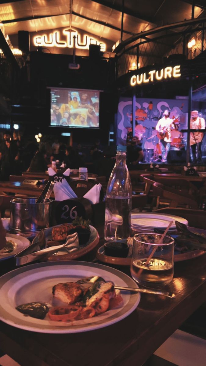 a table topped with plates of food next to bottles of water and glasses filled with liquid