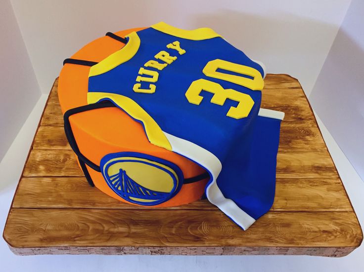 a cake that is sitting on top of a wooden board with a basketball jersey on it