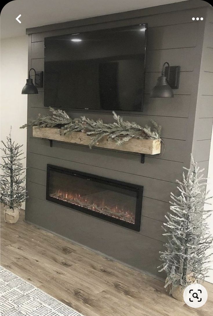 a living room with a fireplace and tv mounted on the wall, decorated for christmas