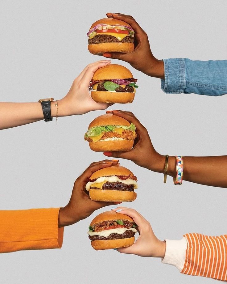 five people holding hamburgers in their hands, each with different toppings on them