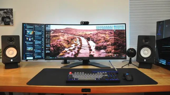 a computer monitor sitting on top of a wooden desk next to speakers and a keyboard