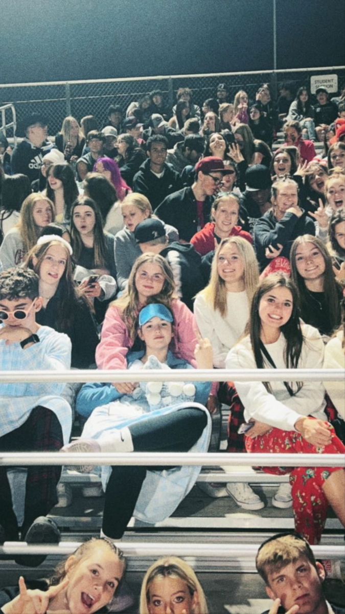 a group of people sitting next to each other in front of a metal fence at a basketball game