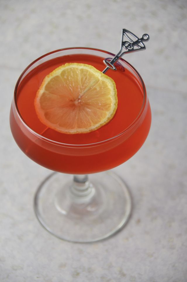 an orange sitting in a wine glass with a scissor sticking out of it