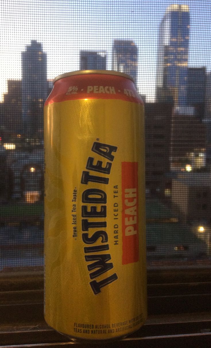 a can of beer sitting on top of a window sill in front of a cityscape