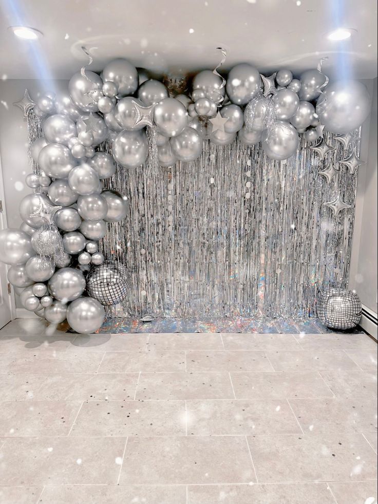 a room filled with lots of shiny silver balls and streamers on the wall next to a white tiled floor