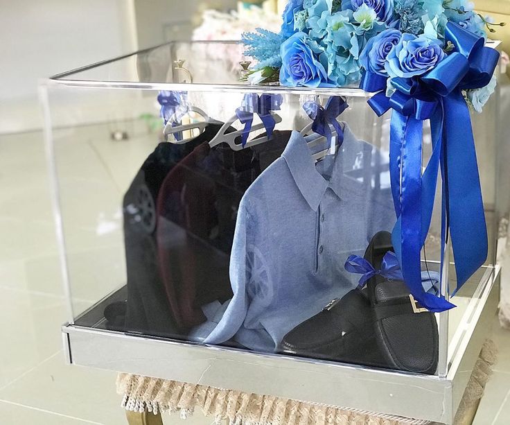 a clear box with blue flowers and clothes hanging on the rack in front of it