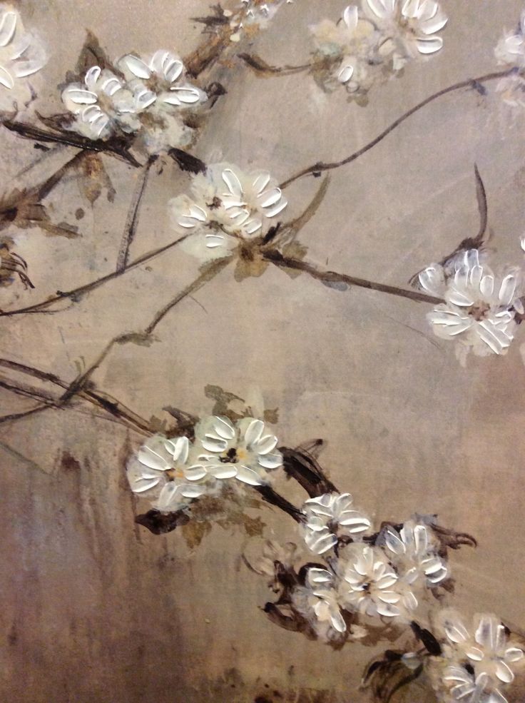 some white flowers are on a branch in front of a brown wall with peeling paint