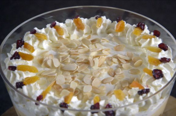 a cake with white frosting and fruit toppings in a glass dish on a table