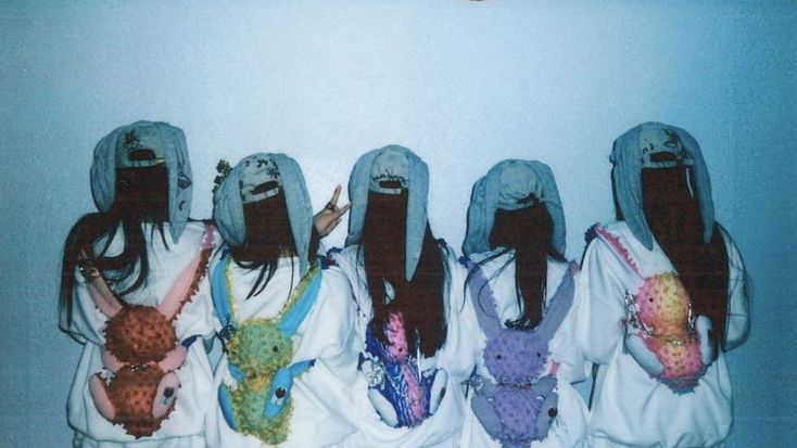 four girls with long hair wearing hoodies and holding their hands in the air while standing next to each other