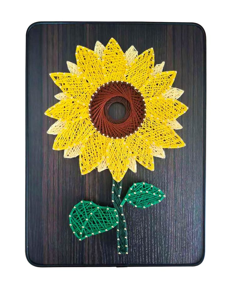 a sunflower made out of yarn on a wooden board with green leaves and beads