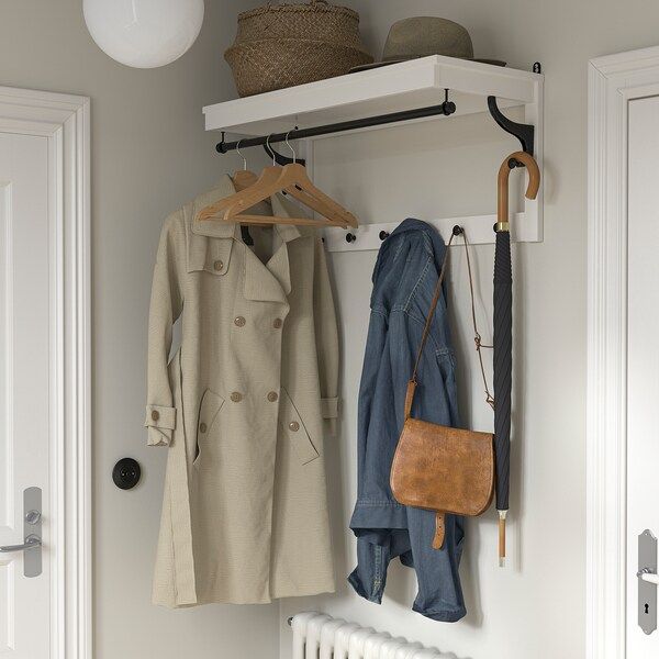 a coat rack with two coats and an umbrella hanging from it's hooks, next to a radiator