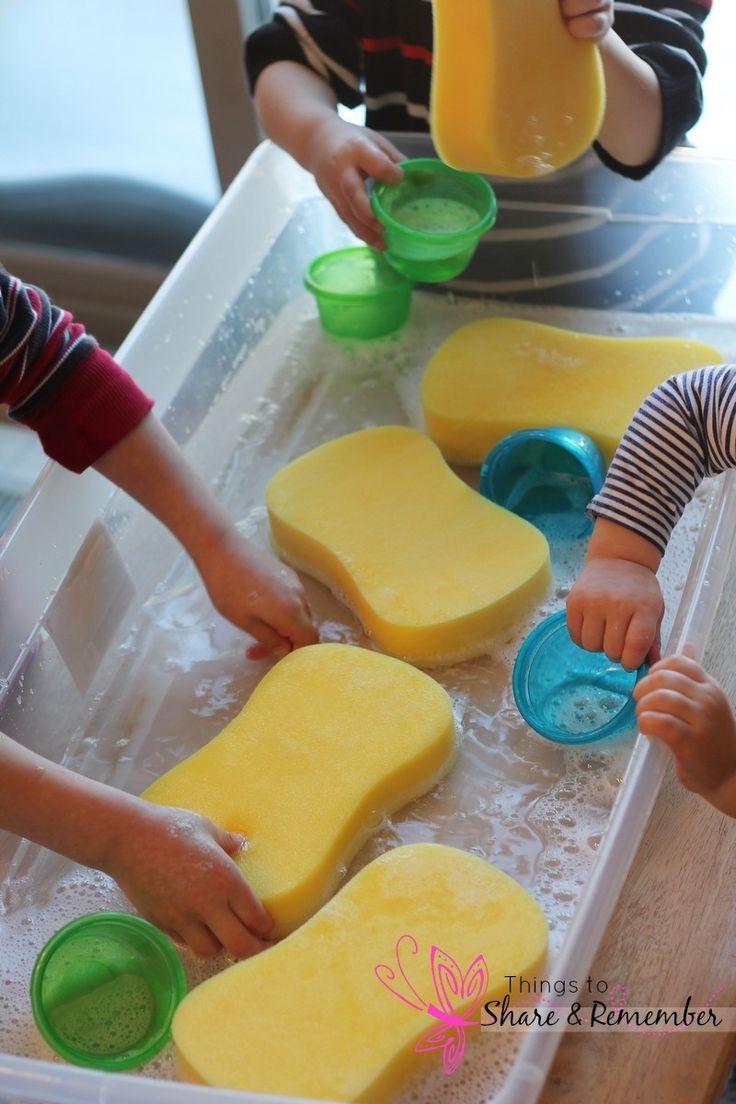 two children are playing with some food on the table and one child is reaching for something