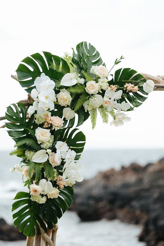 white flowers and greenery decorate the top of a wooden pole near the water's edge