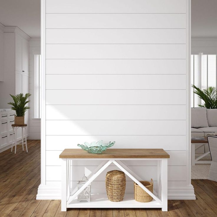 a room with white walls and wood flooring has a wooden table in the center