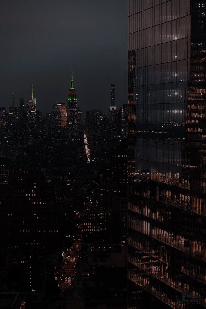 an aerial view of the city at night with buildings lit up in green and white