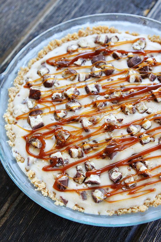 a pie with caramel drizzled on top sitting on a wooden table