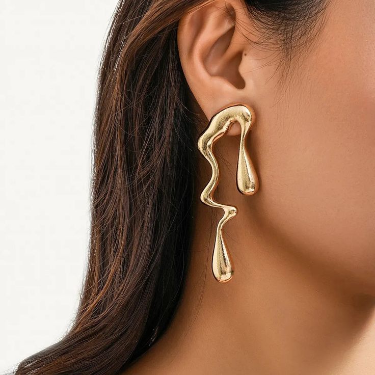 Molten Gold Drip Earrings The earrings are a masterpiece of fluid artistry, designed to give the illusion of molten gold frozen in time as it drips elegantly from the ear. The high-shine finish on theese earrings enhances their liquid metal appearance, providing a dynamic and sculptural quality to the accessory. This daring pair makes a bold fashion statement, perfect for anyone looking to add a touch of avant-garde sophistication to their attire. They are particularly suited for evening events where their dramatic flair can be fully appreciated. Abstract Earrings, Statement Drop Earrings, Popular Fashion, Stud Earrings For Women, Trendy Earrings, Gold Geometric, Earring Type, Fashion Jewelry Earrings, Metal Earrings