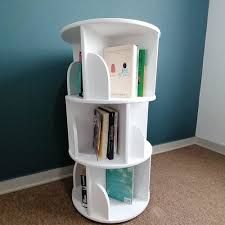 a white book shelf with books on it in a corner next to a blue wall