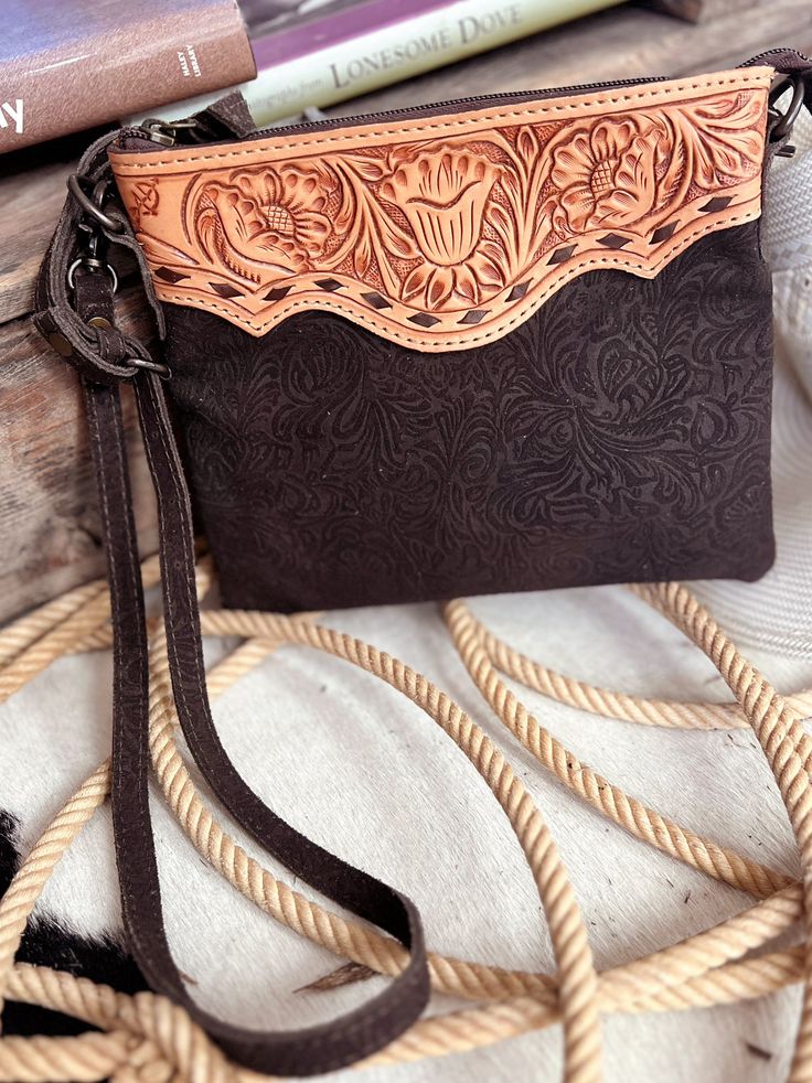 Darling Tooled Not Fooled Leather Crossbody Bag | Gussied Up Online Indulge in the timeless elegance of the Darling Tooled Not Fooled Leather Crossbody. Crafted from high quality, genuine leather, this western-style bag boasts a beautiful tan tooled trim and a rich chocolate brown embossed suede body. With a removable and adjustable strap, and a convenient zip-top closure, this pouch-style bag is both stylish and functional. One compartment with an inside zipper pocket, outside zipper pocket and Hand Tooled Western Bags, Hand-tooled Leather Bags For Western-themed Events, Hand Tooled Leather Bags For Western-themed Events, Leather Hand Tooled Shoulder Bag For Western-themed Events, Western Brown Bag With Adjustable Strap, Hand-tooled Saddle Bags, Western-themed Brown Leather Shoulder Bag, Brown Rectangular Bag For Rodeo, Rectangular Brown Bag For Rodeo